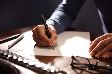 Individual using a pen to write an invitation letter on paper